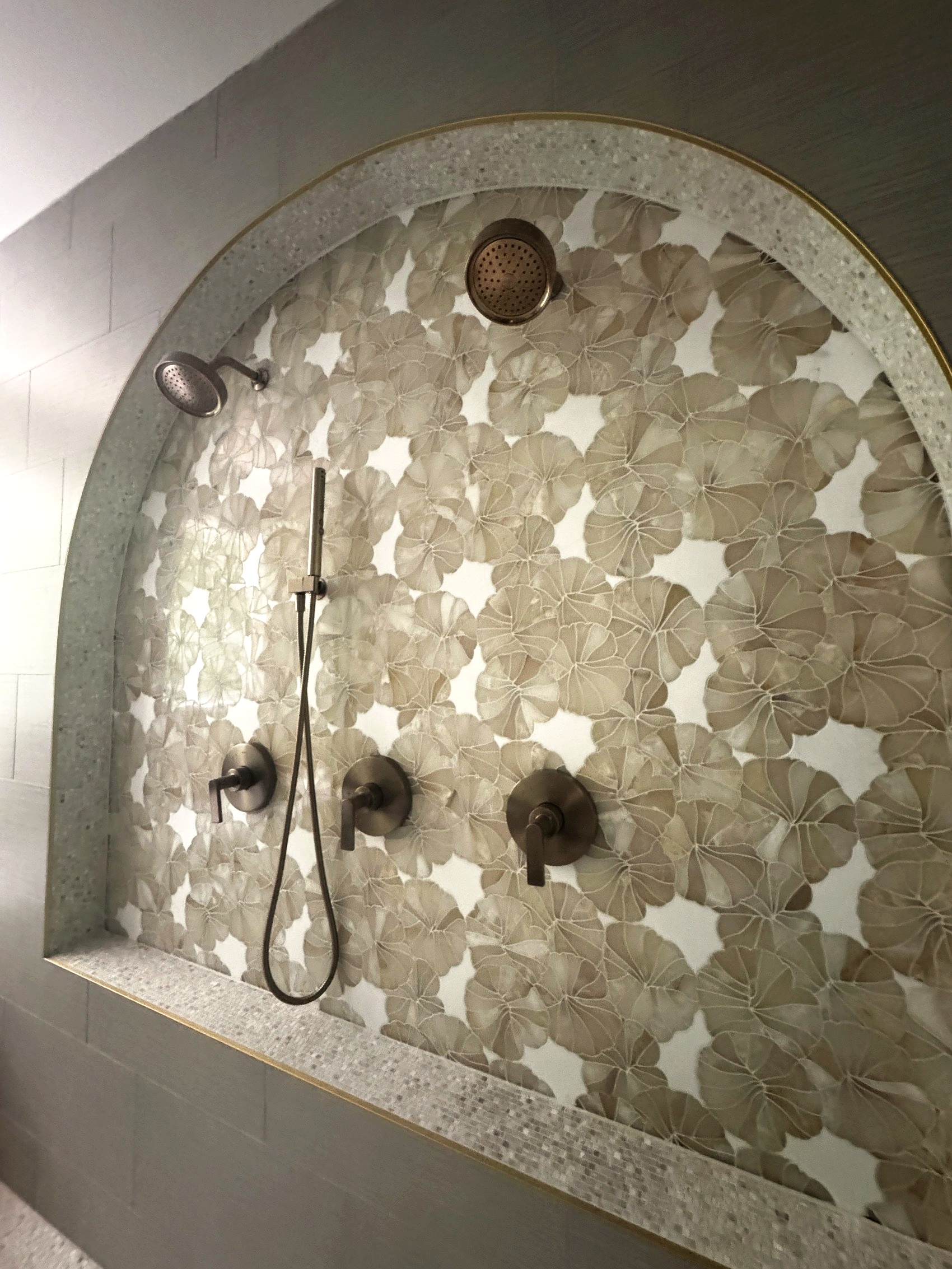 Detail of mosaic tile and fixtures in the arched shower niche.