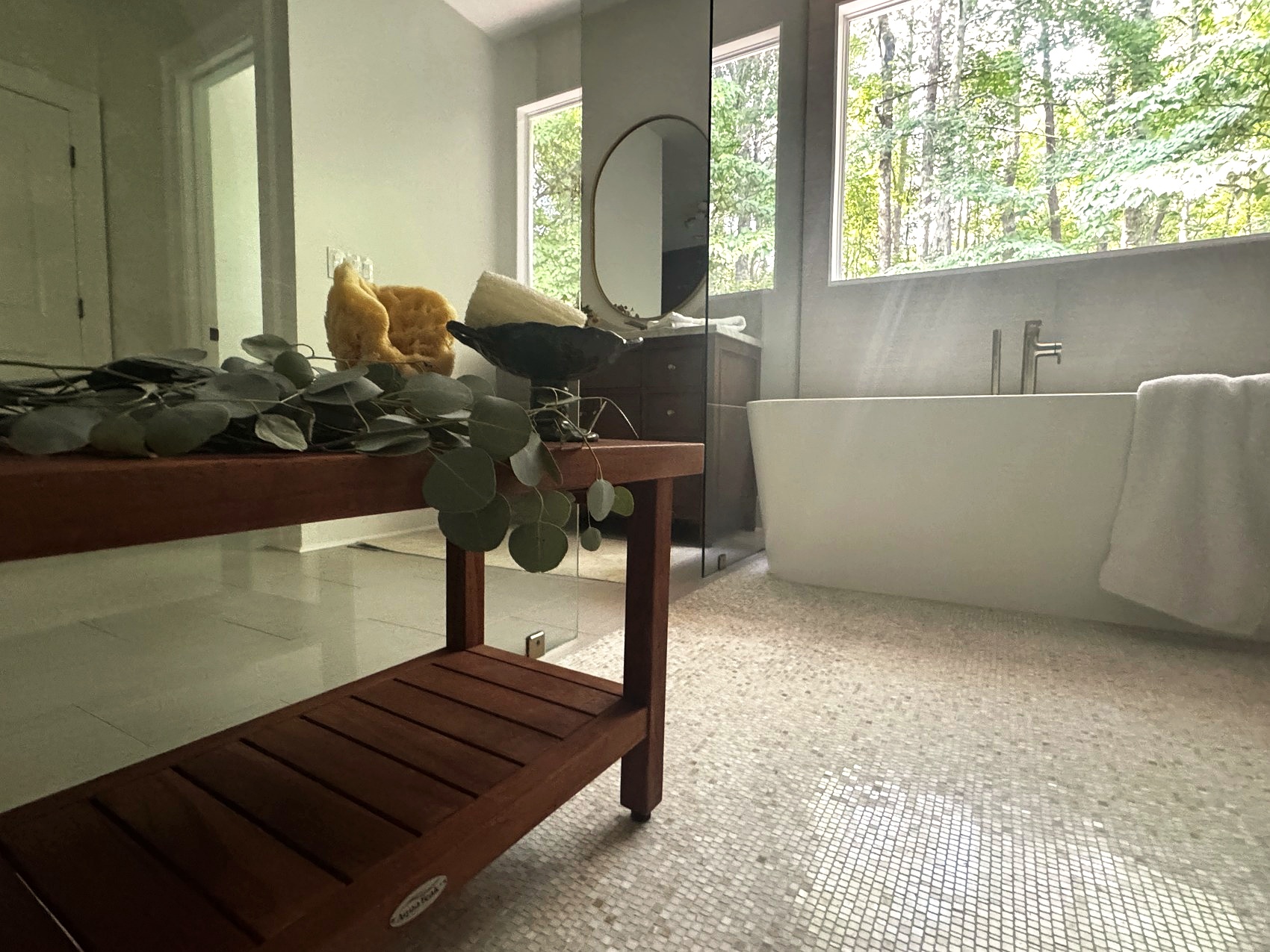 Teak shower bench styled with natural sponges and eucalyptus.