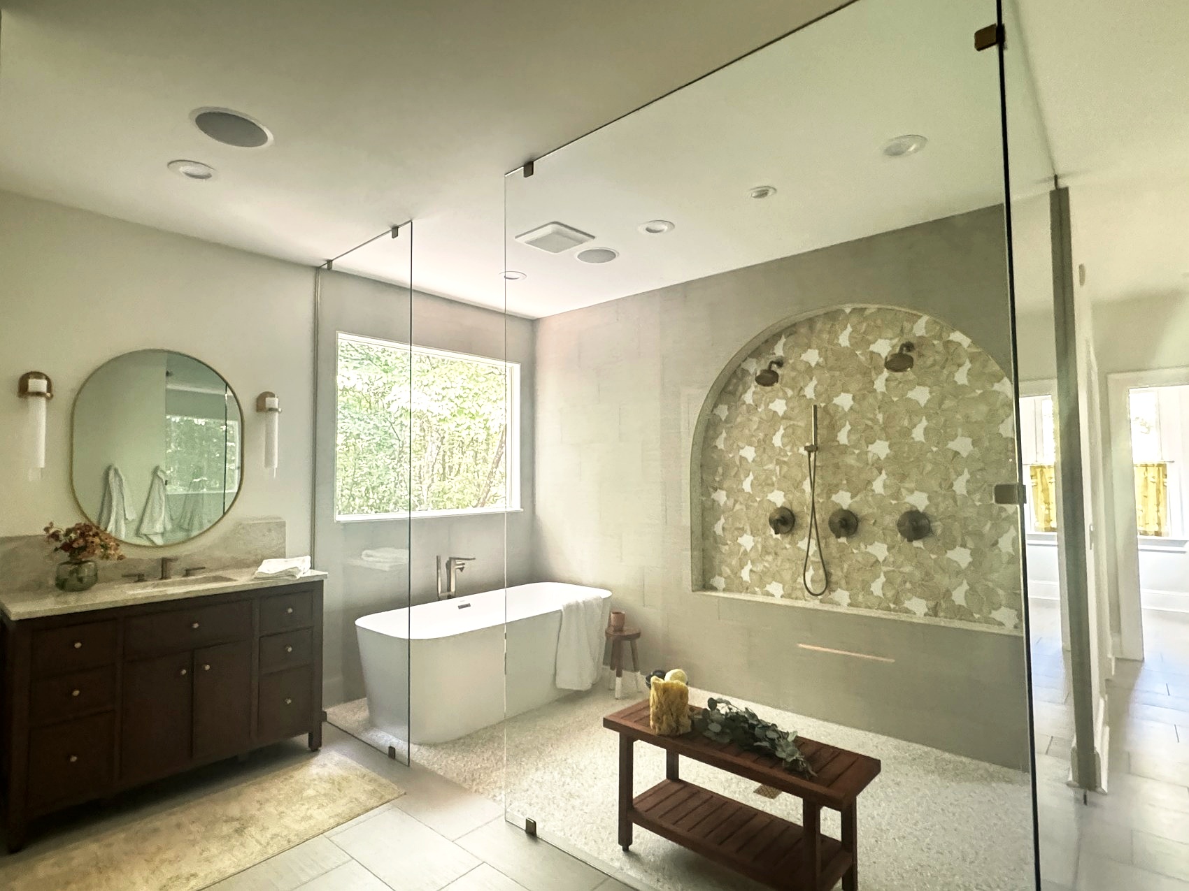 A primary bathroom suite with a soaking tub and walnut vanity.
