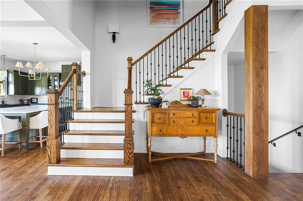 Entry staircase with an antique console table, opening to the kitchen.