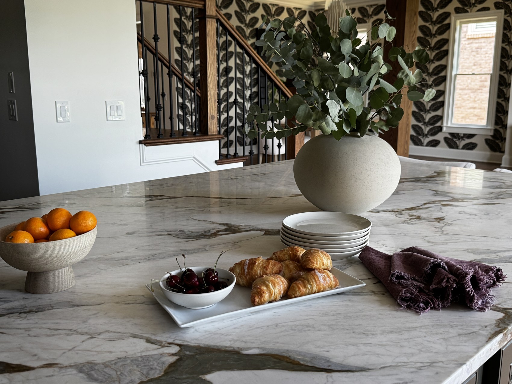 Wide view of olive green kitchen with double ovens and marble island.