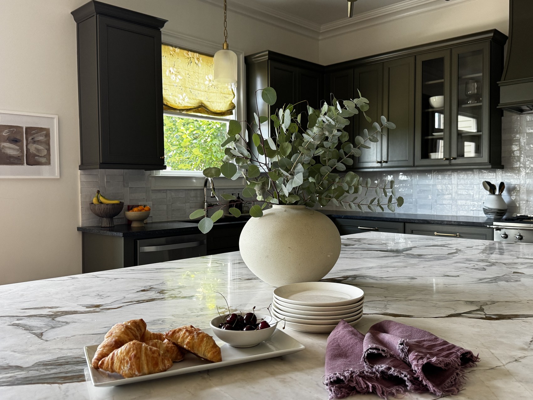 Kitchen island with fruit bowl and marble waterfall countertop.