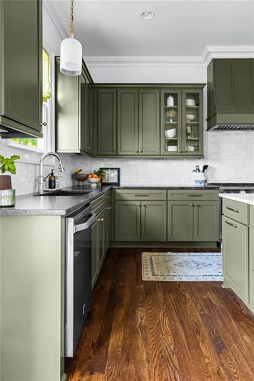 Sage green kitchen cabinetry with white subway tile backsplash.