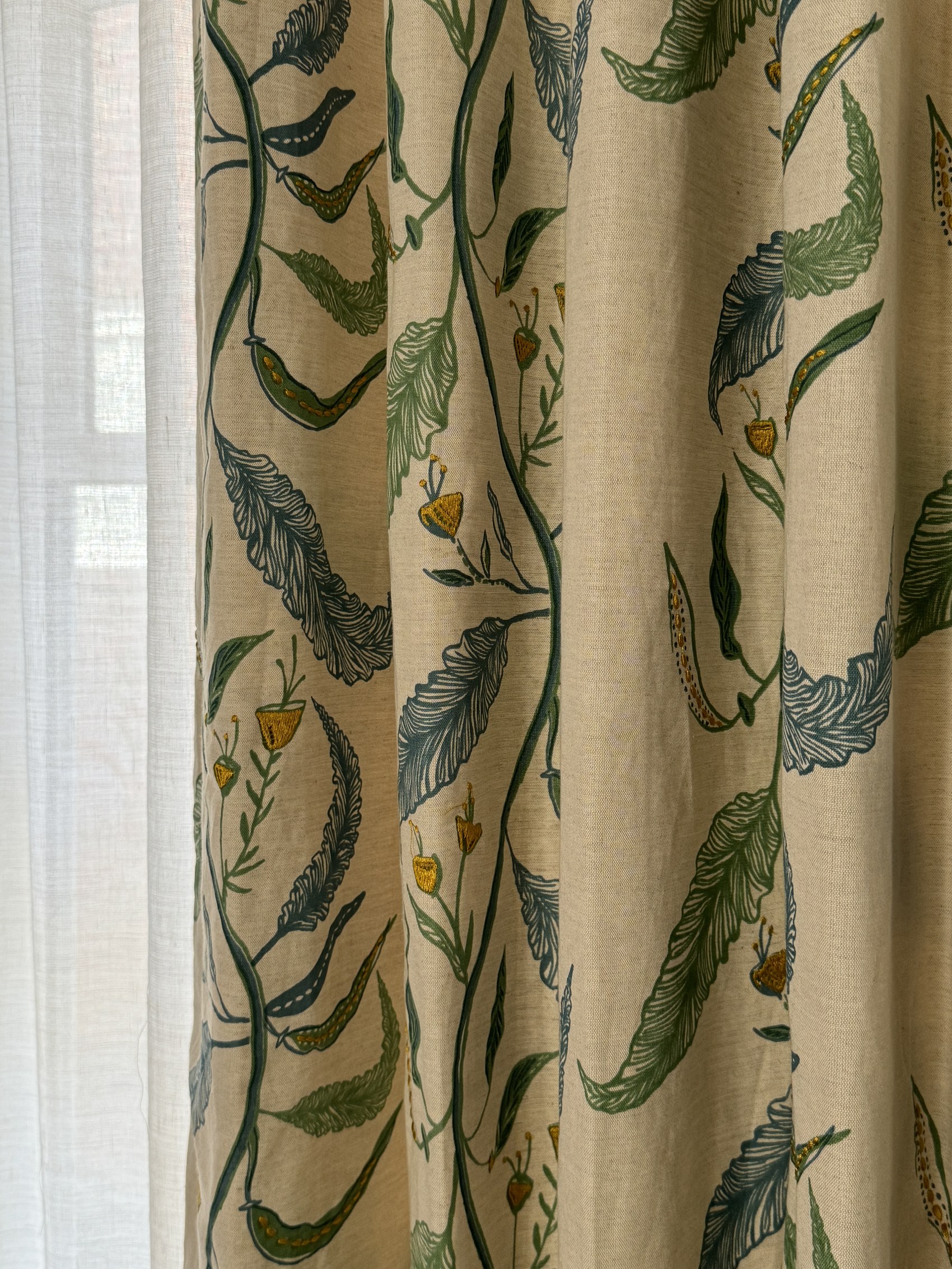 Detail of botanical curtain fabric with hand-embroidered leaves and blossoms.