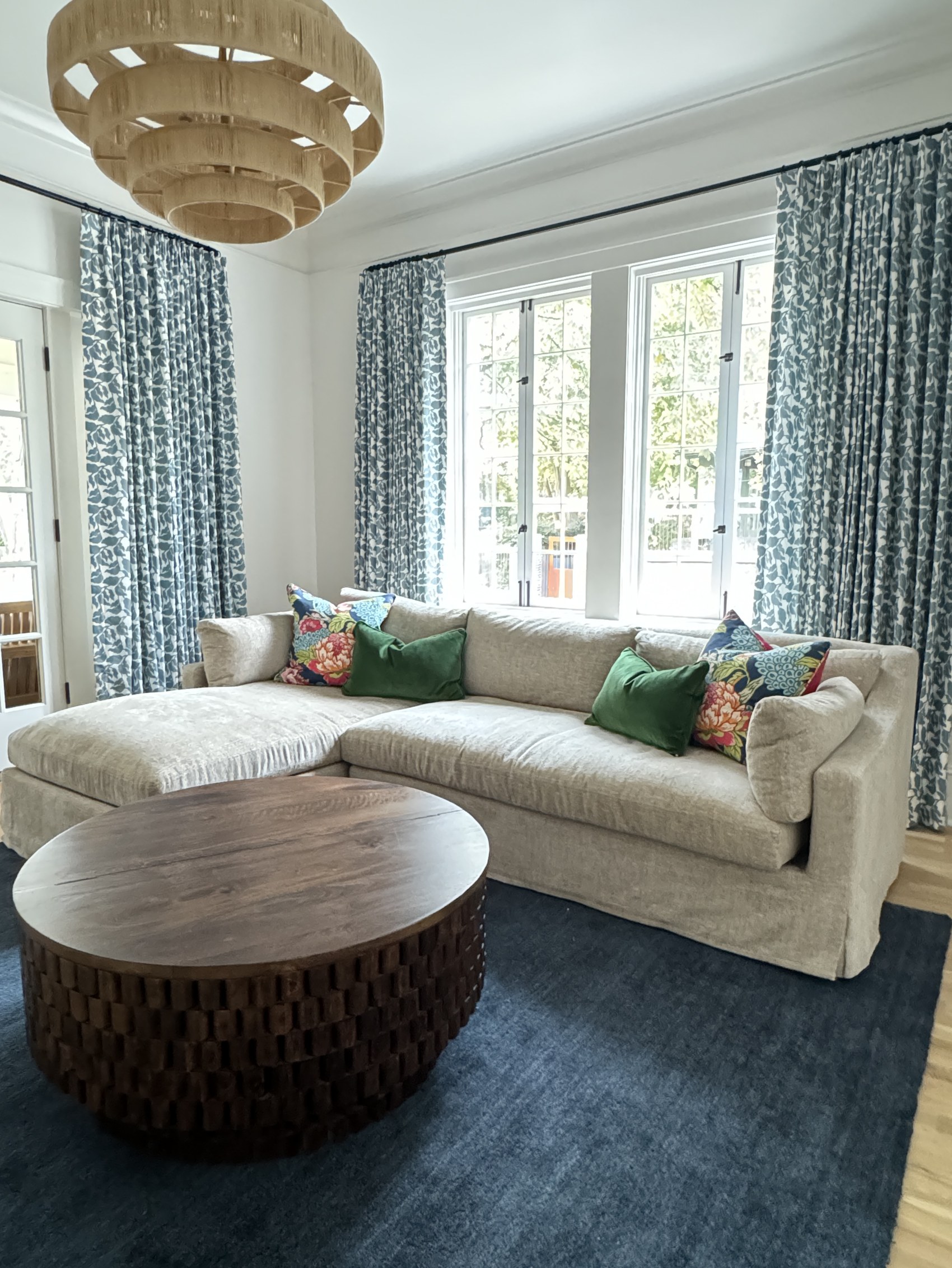 A layered living room with a floral-print sectional and brass pendant.