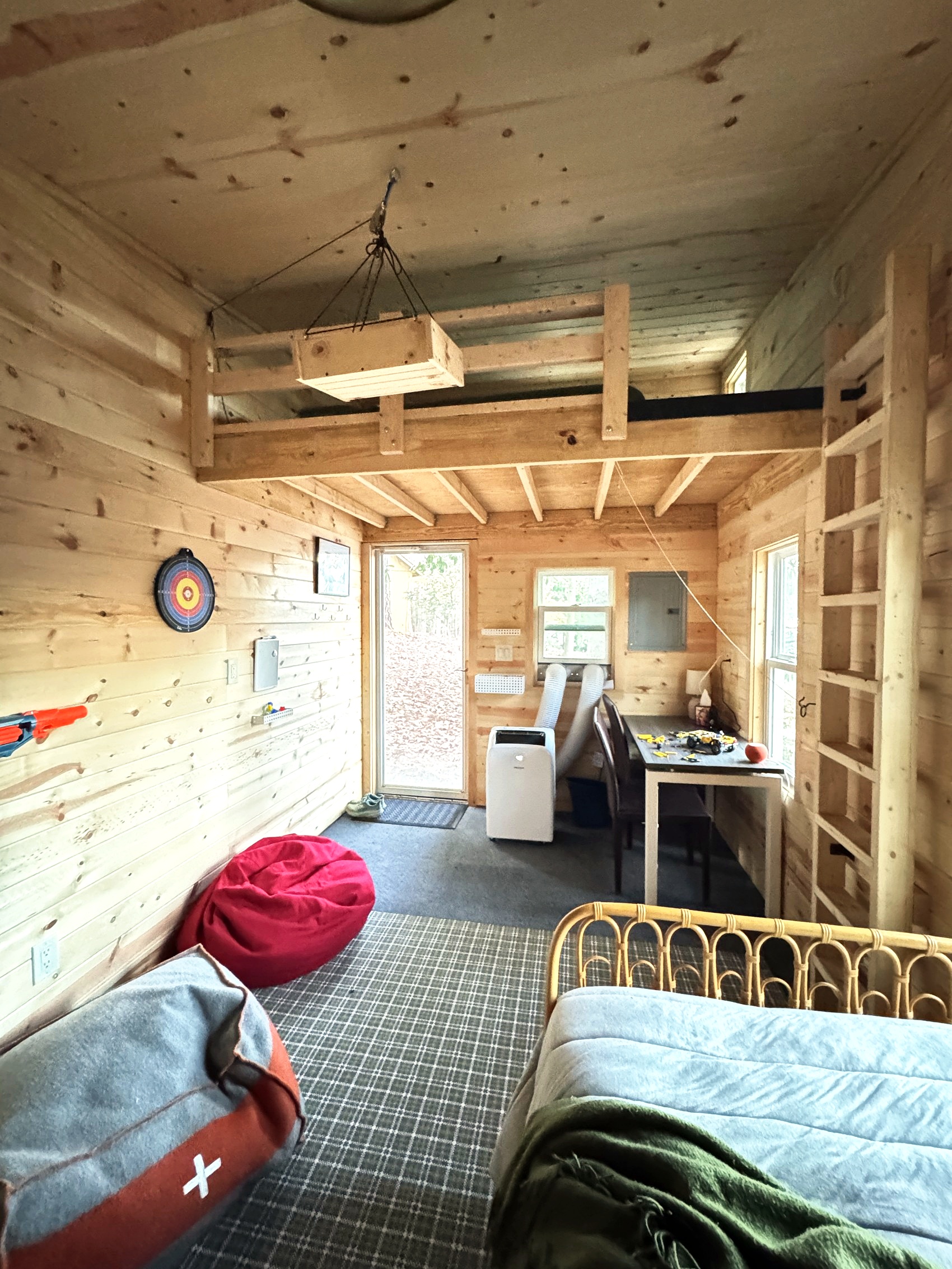 Bunkhouse bedroom with a sleeping loft, dartboard, and desk area.