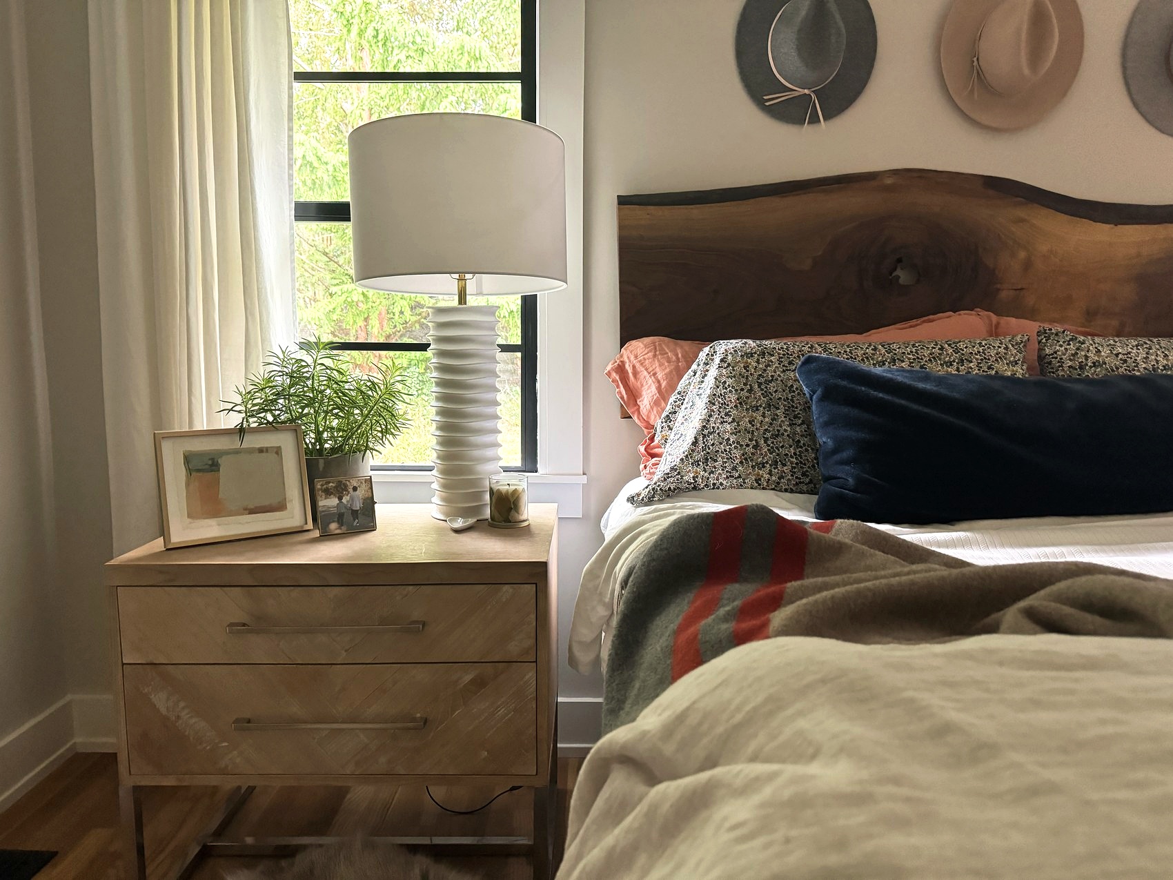 Guest bedroom nightstand with a ribbed lamp and potted plant.