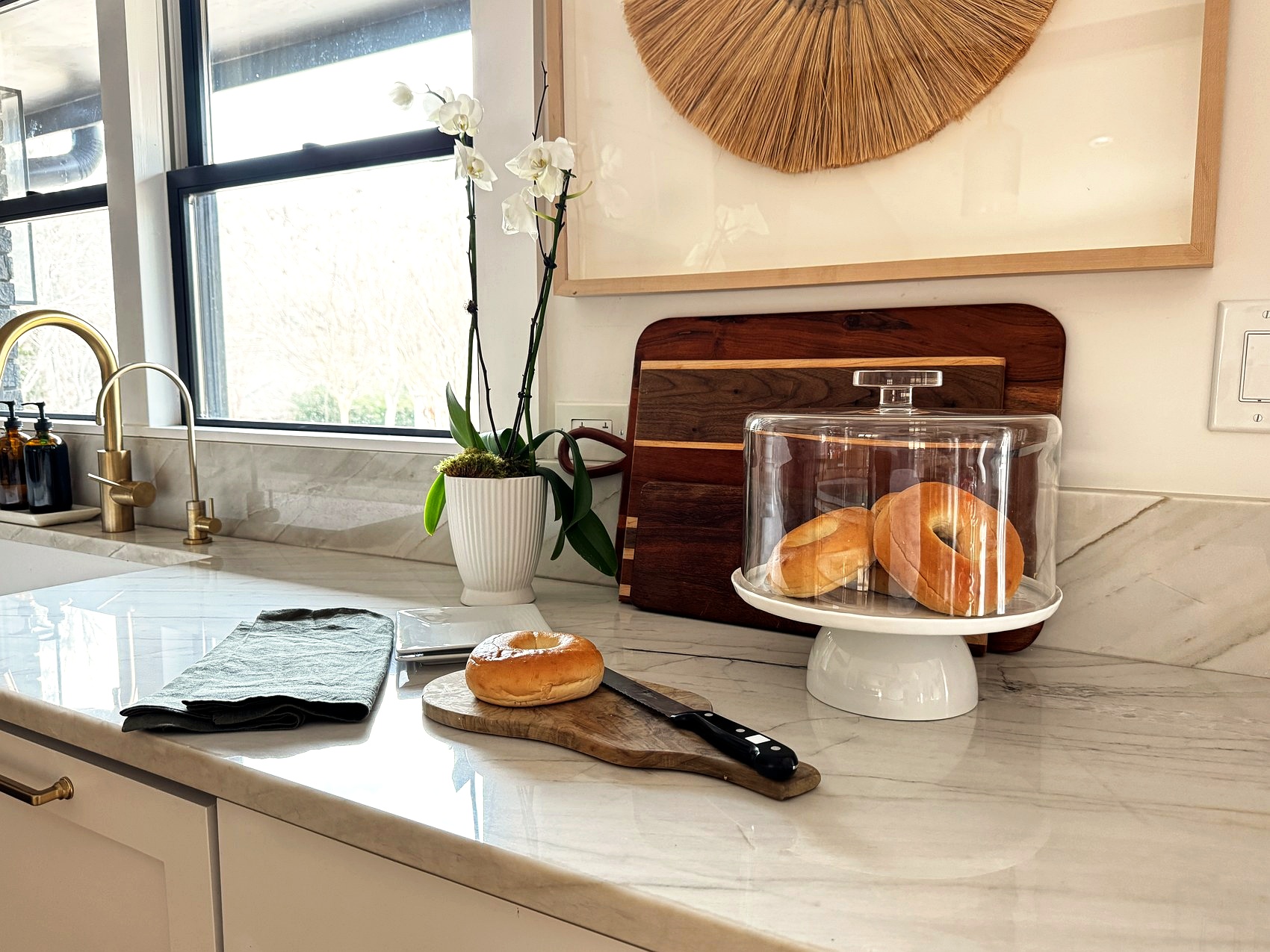 Kitchen counter styled with bagels, cutting boards, and an orchid.