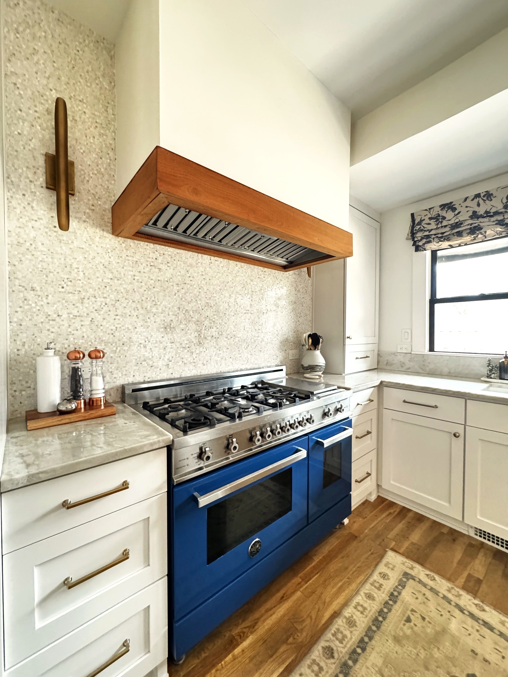Kitchen range hood detail with brass sconces and mosaic tile backsplash.