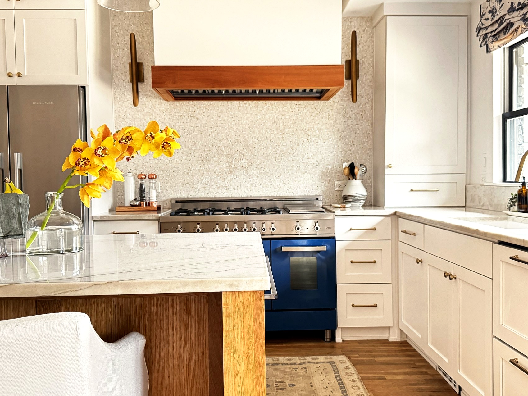 Kitchen island detail with yellow orchids and a navy range in the background.