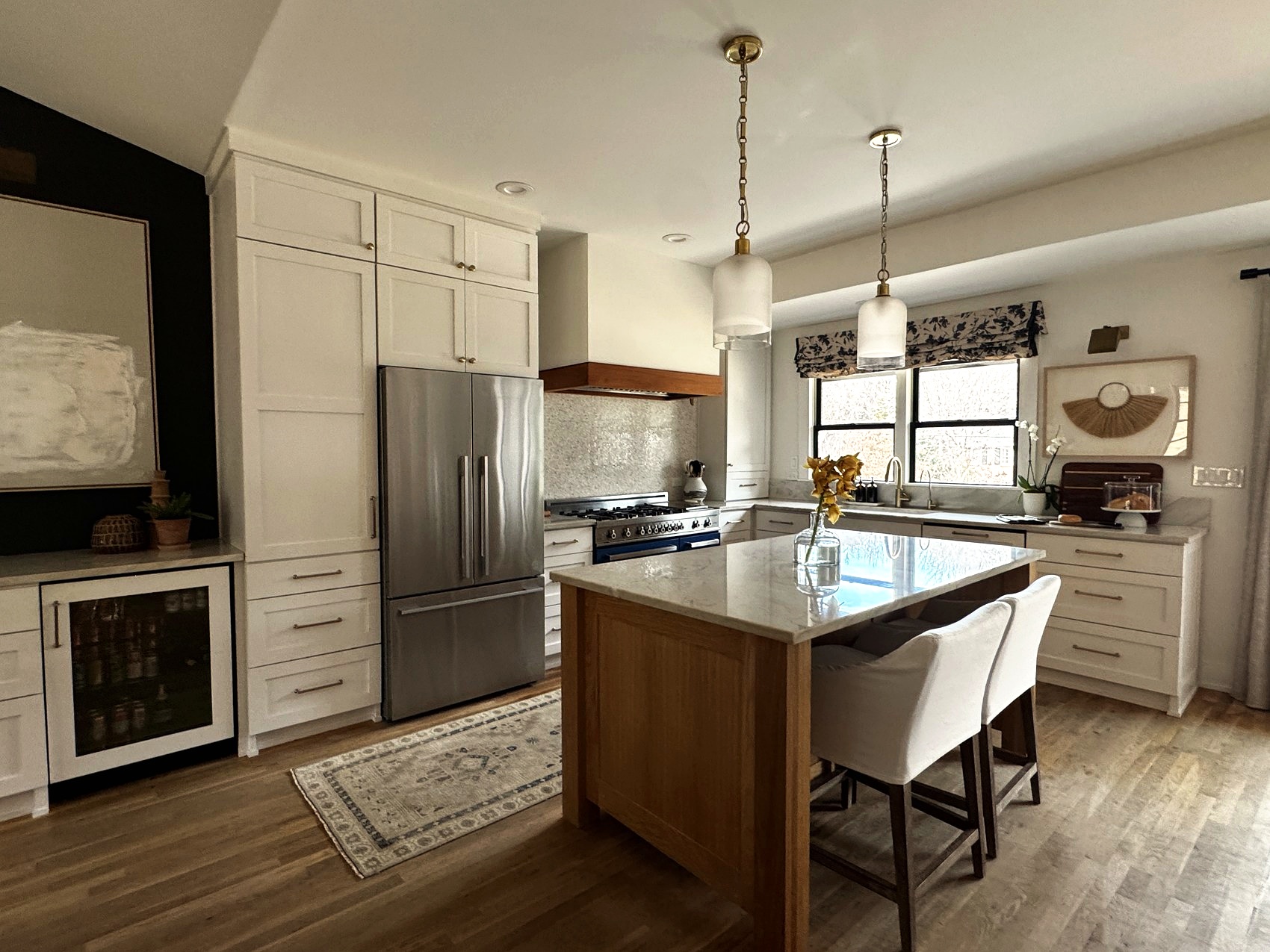Kitchen with white cabinetry, a navy range, and a marble waterfall island.