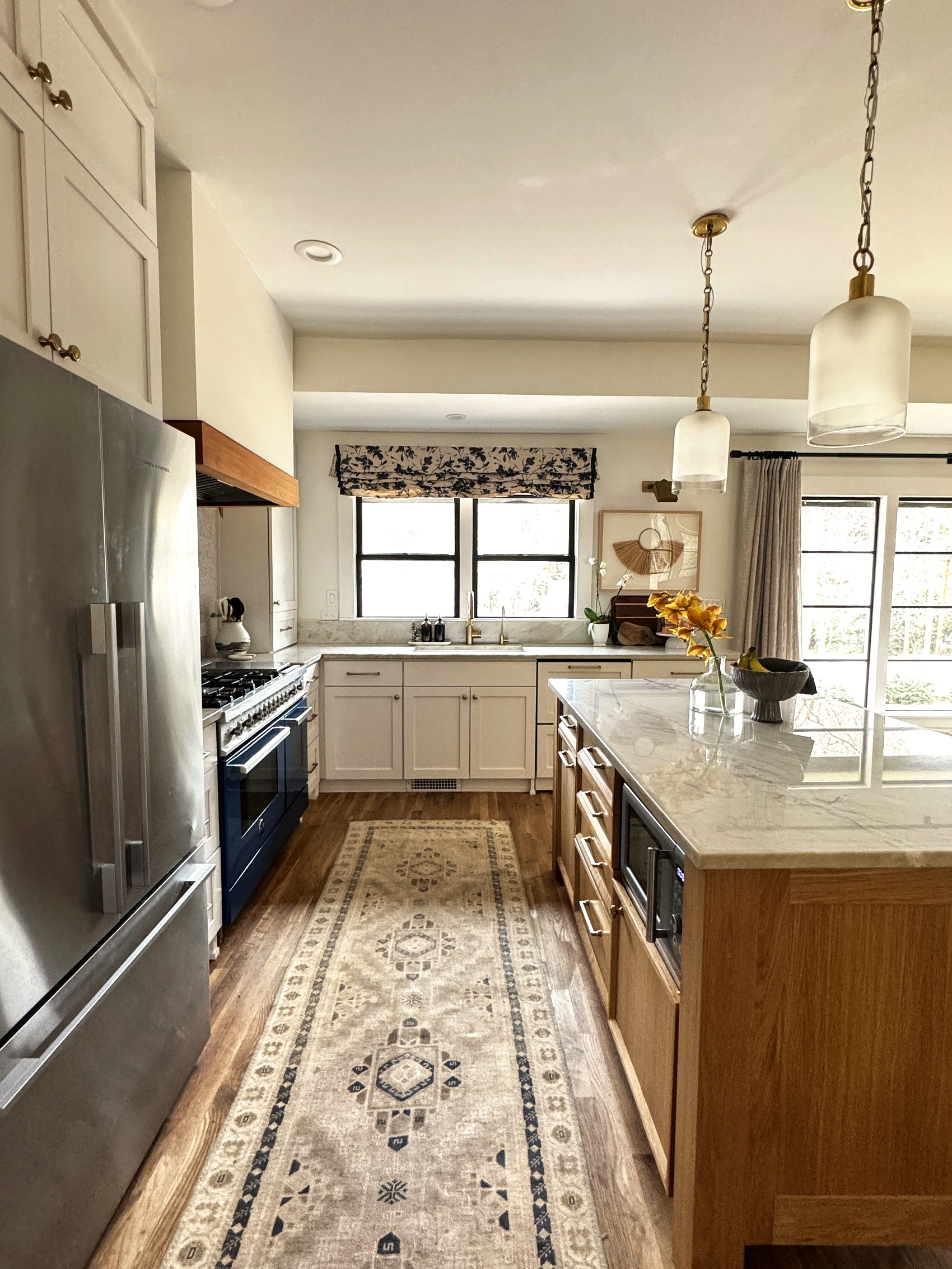 Wide view of the kitchen with island seating and pendant lights.