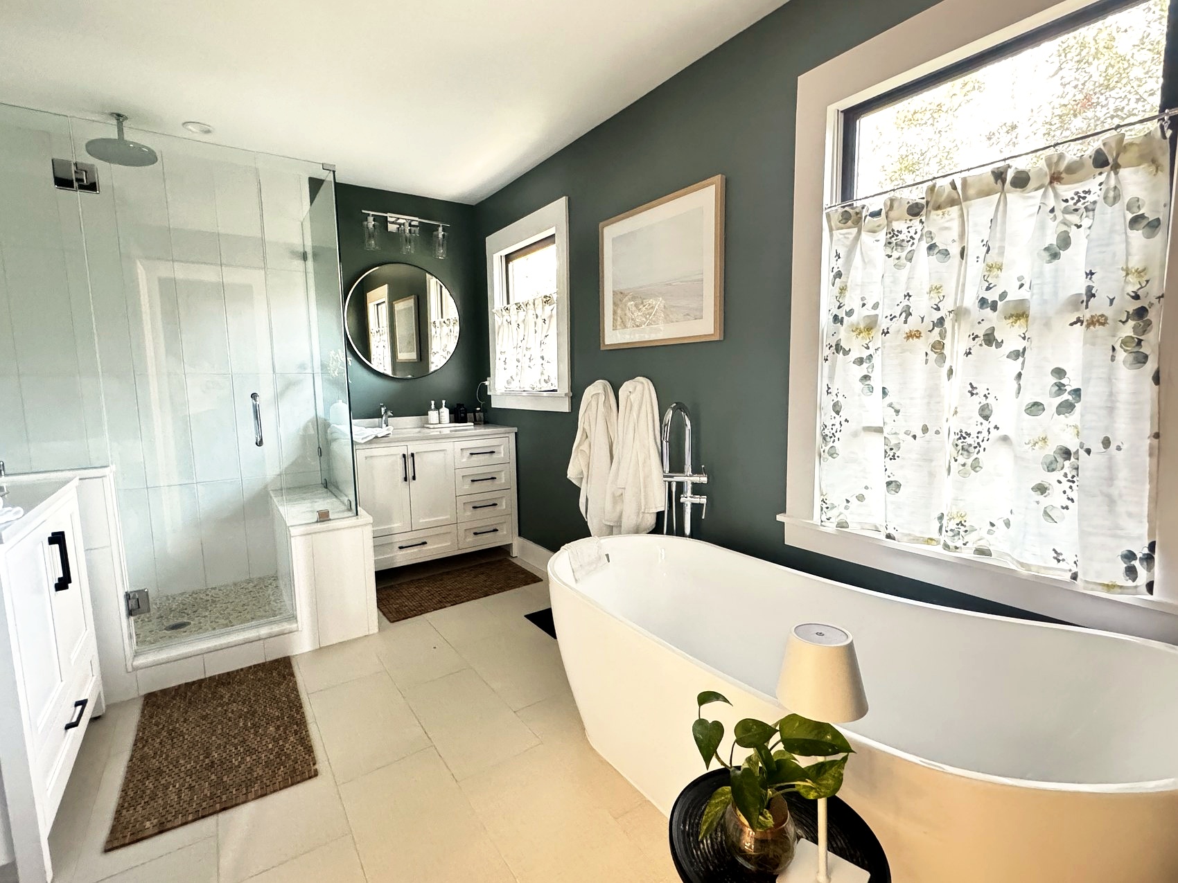 Primary bathroom with sage green walls, a glass shower, and freestanding tub.