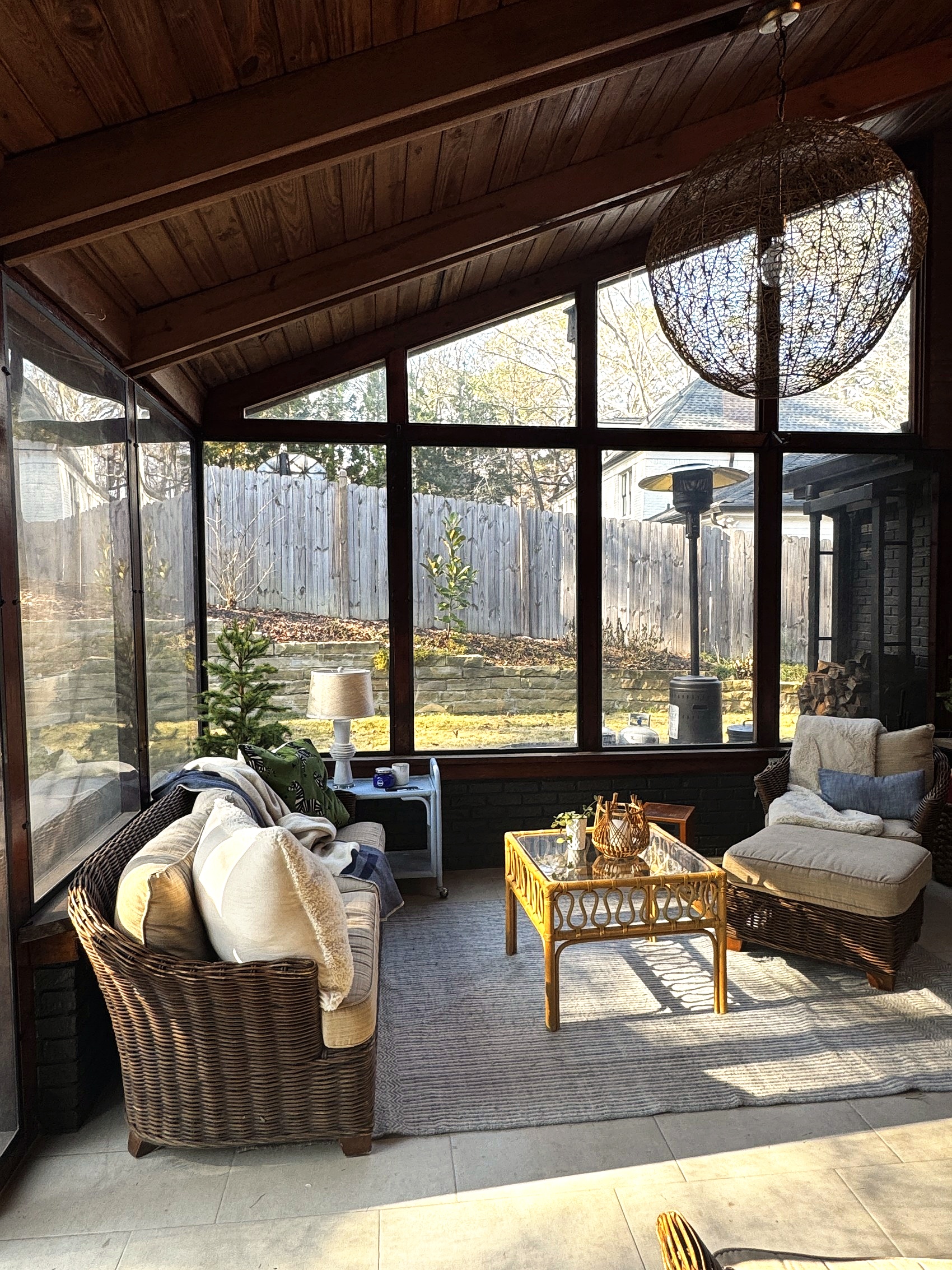 Screened sunroom with wicker furniture and a woven pendant light.