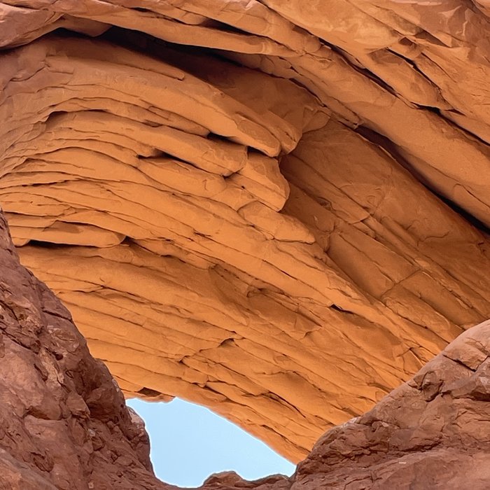 Sunlight through a red sandstone arch, looking up.