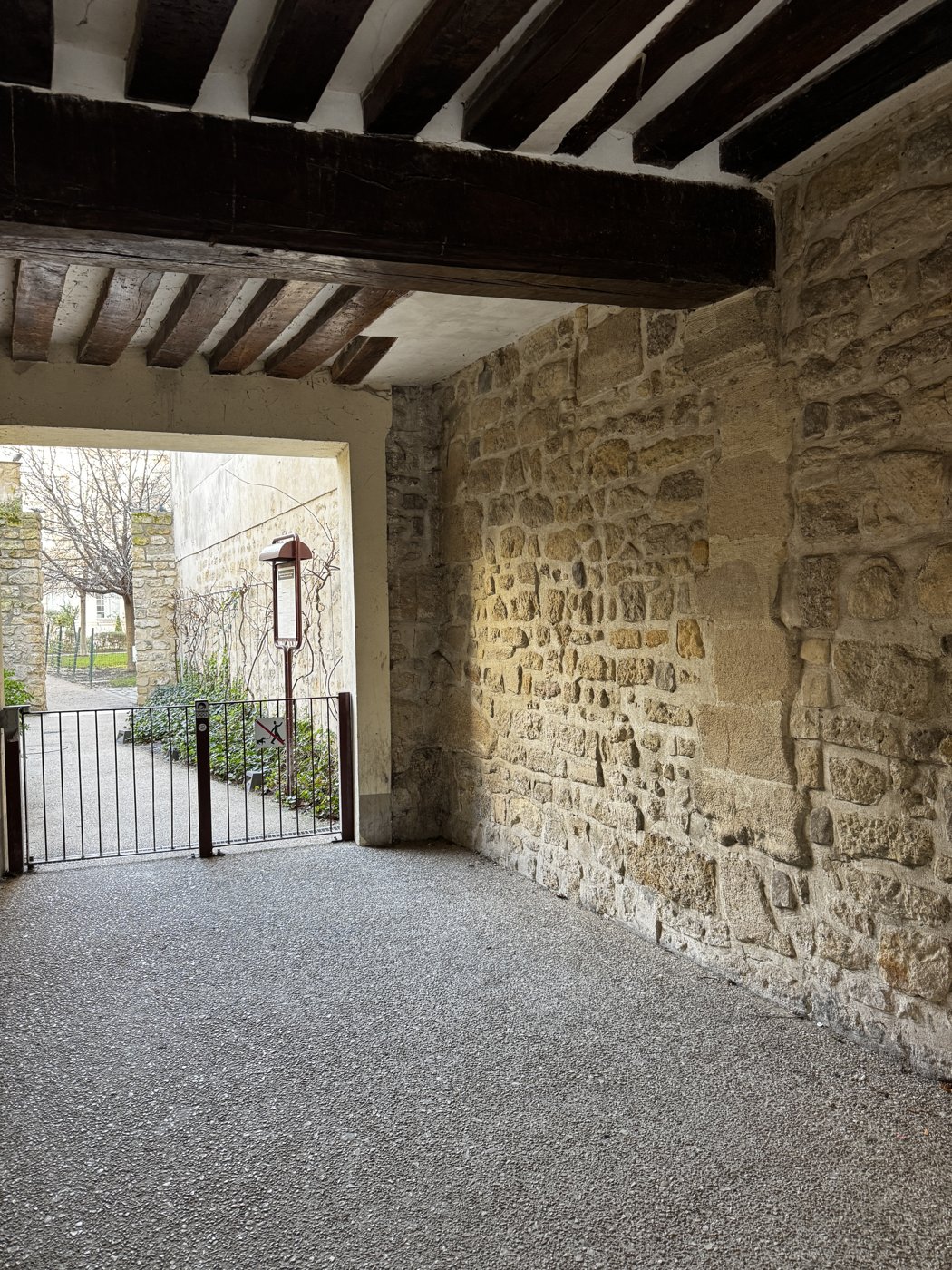 A timber-beamed stone passageway opening onto a quiet courtyard.